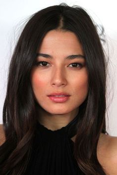 Woman with long dark hair wearing a black top, looking directly at the camera