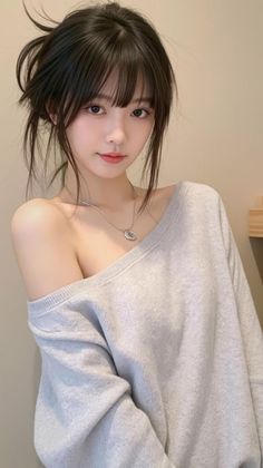 Woman with black hair in an off-shoulder sweater and silver necklace