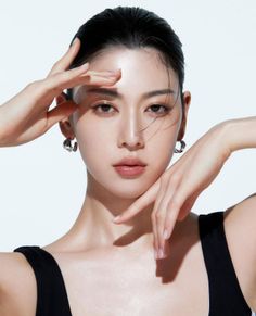 Woman with black hair and earrings posing against a white background