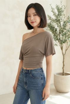 Woman with short hair wearing an off-shoulder top and blue jeans indoors
