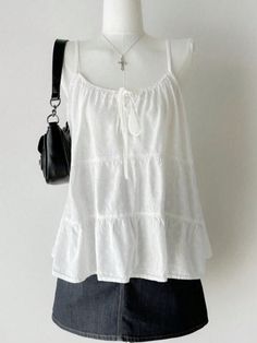 White tiered top and denim skirt on a mannequin with a cross necklace and black bag
