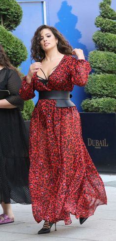 Woman in a red leopard print dress with a black corset belt and high heels
