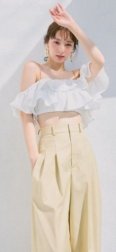 Woman in a white off-shoulder ruffle top and high-waisted pants outdoors