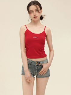 Woman in a red camisole and denim shorts posing in a studio