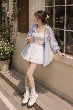 Woman in a white mini skirt and striped shirt holding a drink outdoors