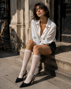 Woman in a white shirt and black skirt sitting on stone steps outdoors