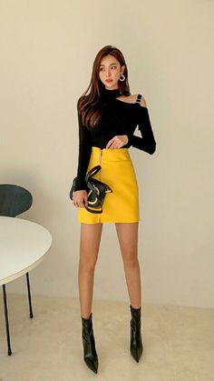 Woman in a black long-sleeve top and yellow mini skirt with ankle boots
