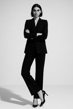 Woman in a black suit and high heels posing in a studio
