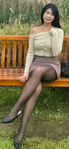 Woman with long black hair sitting on a wooden bench outdoors