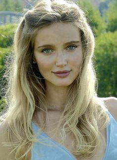 Blonde woman with green eyes and long hair in a blue dress outdoors