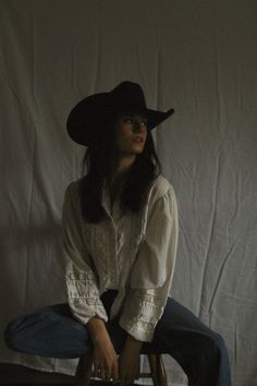 Woman in a cowboy hat and white shirt sitting indoors