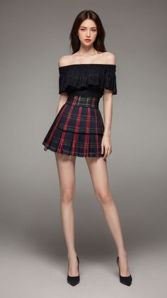 Woman in an off-shoulder top and plaid skirt posing in a studio