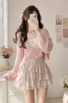 Woman in a pink cardigan and ruffle skirt taking a mirror selfie