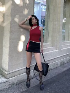 Woman in a red top and black mini skirt with lace socks posing outdoors