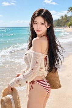 Woman in a bikini and sheer top on a sunny beach holding a straw hat