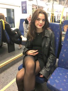 Woman with long hair wearing a leather jacket and tights on a train