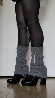 Person wearing black tights, chunky heels, and grey leg warmers with charms