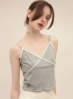 Woman wearing a grey camisole with white lace trim and a lace choker