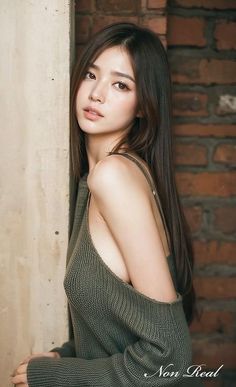 Woman with long hair in a knitted top leaning against a wall