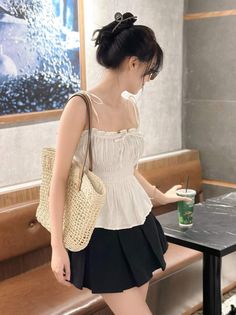 Woman in a white top and black skirt holding a drink indoors