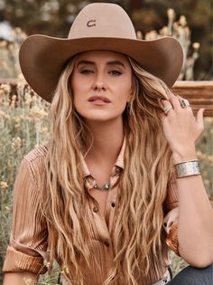 Woman with long blonde hair and a cowboy hat in a field