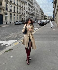 Woman in a trench coat and red boots walking on a city street