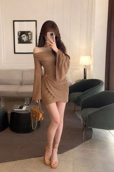 Woman in a brown off-shoulder mini dress and high heels holding a small bag