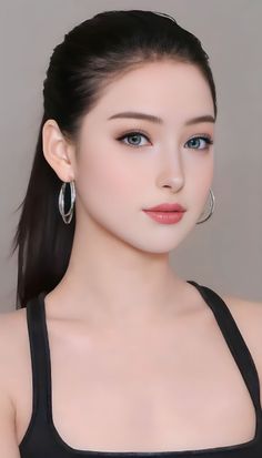 Woman with black hair in a ponytail wearing a black top and hoop earrings
