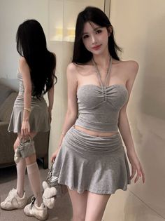 Woman in a gray halter top and mini skirt posing in front of a mirror