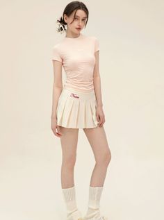 Woman in a pink top and pleated skirt with leg warmers in a studio