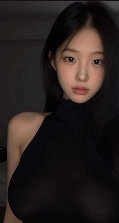 Woman with long black hair wearing a black top in soft lighting