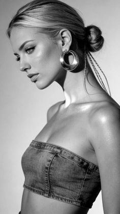 Woman in a denim strapless top with a bun and large hoop earrings