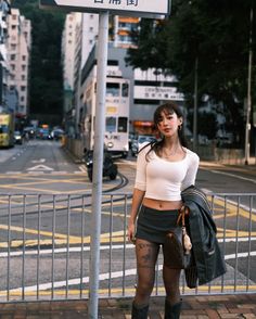 Woman in a white crop top and mini skirt standing on a city street