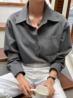 Person in a gray shirt and white pants holding a white mug