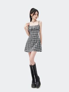 Woman in a plaid dress and black boots posing against a white background