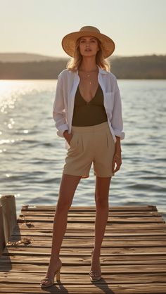 Woman in a straw hat and white shirt standing on a pier at golden hour