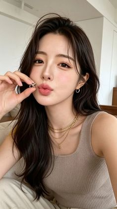 Woman with long dark hair wearing a ribbed tank top and gold necklaces