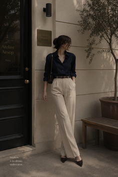 Woman in a dark blue shirt and beige pants standing outdoors