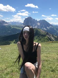 Woman with long black hair and a headband posing in a mountain landscape