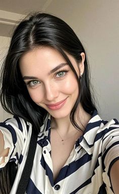 Woman with long black hair and green eyes wearing a striped shirt, smiling