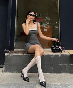 Woman in a mini dress and lace socks sitting outdoors