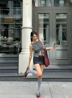 Woman in a gray crop top and pinstripe mini skirt posing outdoors
