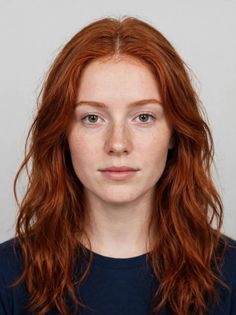Woman with red wavy hair and green eyes looking directly at the camera