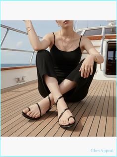 Woman in a black camisole and pants sitting on a boat deck