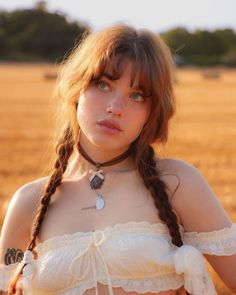 Woman with red hair and braids wearing an off-shoulder top outdoors