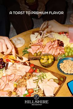 Multiple hands reaching for food on a large charcuterie board