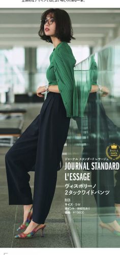 Woman with short hair and glasses wearing a green cardigan and wide leg pants