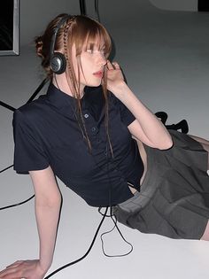 Woman with headphones and a pleated skirt lying on a white floor