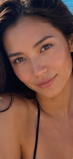 Woman with long dark hair wearing a black bikini top outdoors
