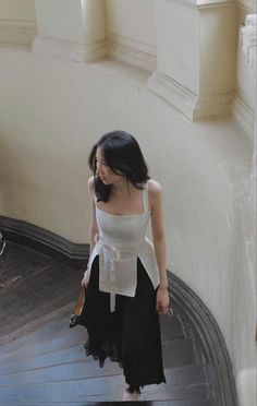 Woman in a white top and black skirt walking down a staircase